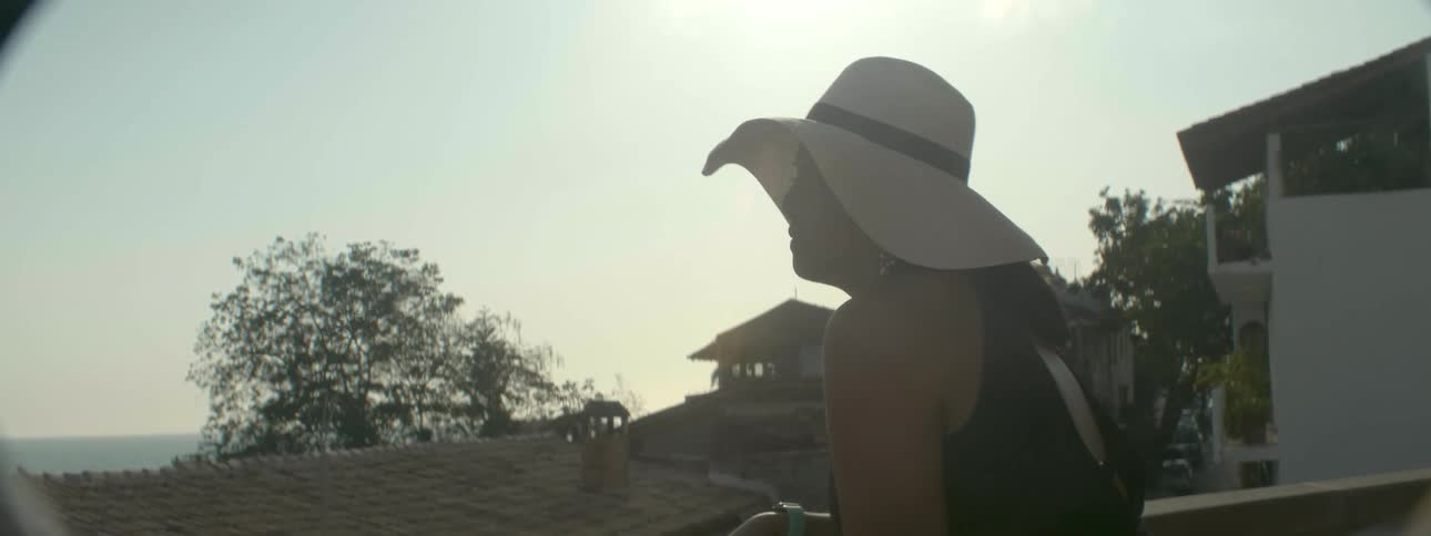 Woman stands on a balcony looking out at rooftops