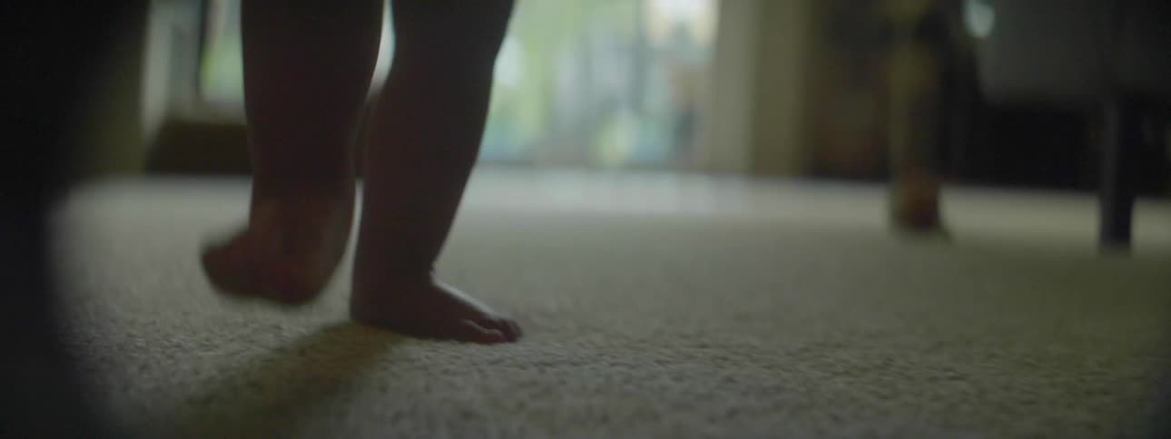 Baby walks over carpet in a house