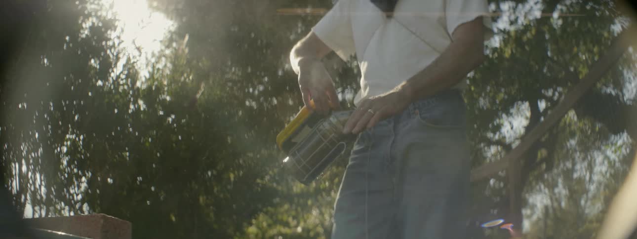A man sprays bees with a smoker