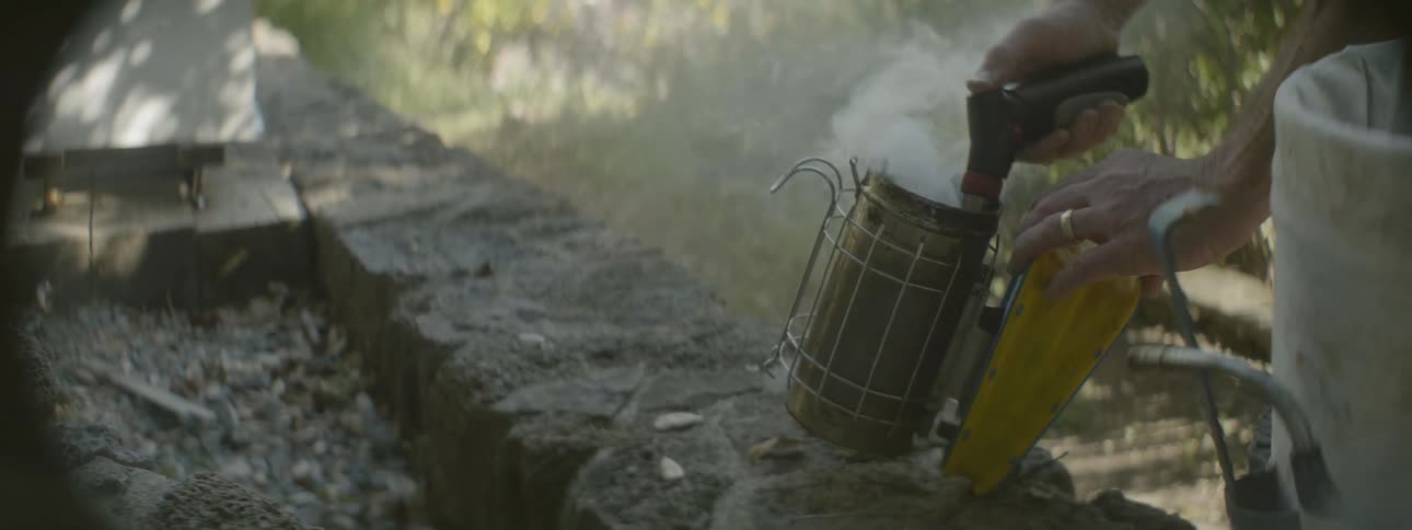 A person lifts a bee steamer and uses it