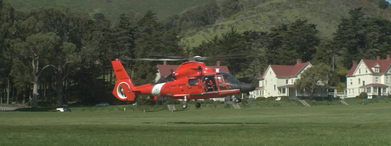 A helicopter is taking off from a field