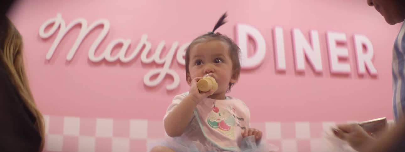 A young baby is sitting on a table eating ice cream