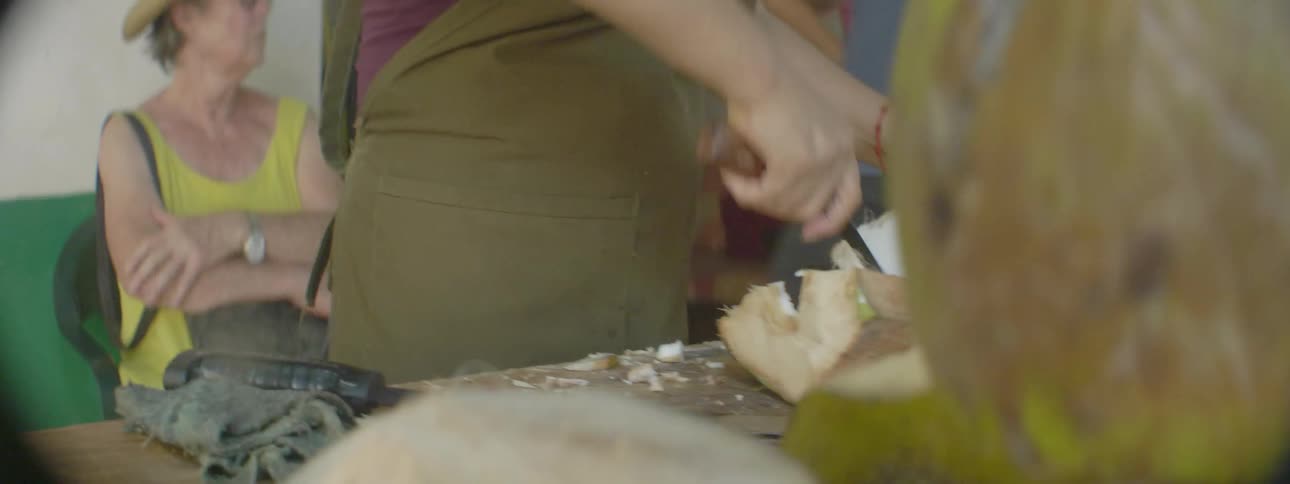 A woman chops a coconut with a machete