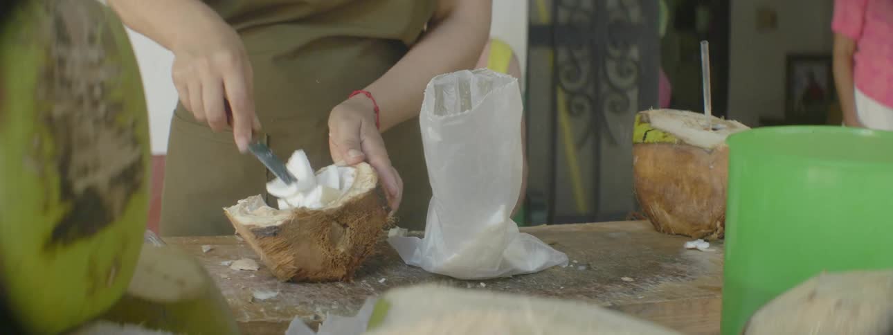 A woman cores a coconut