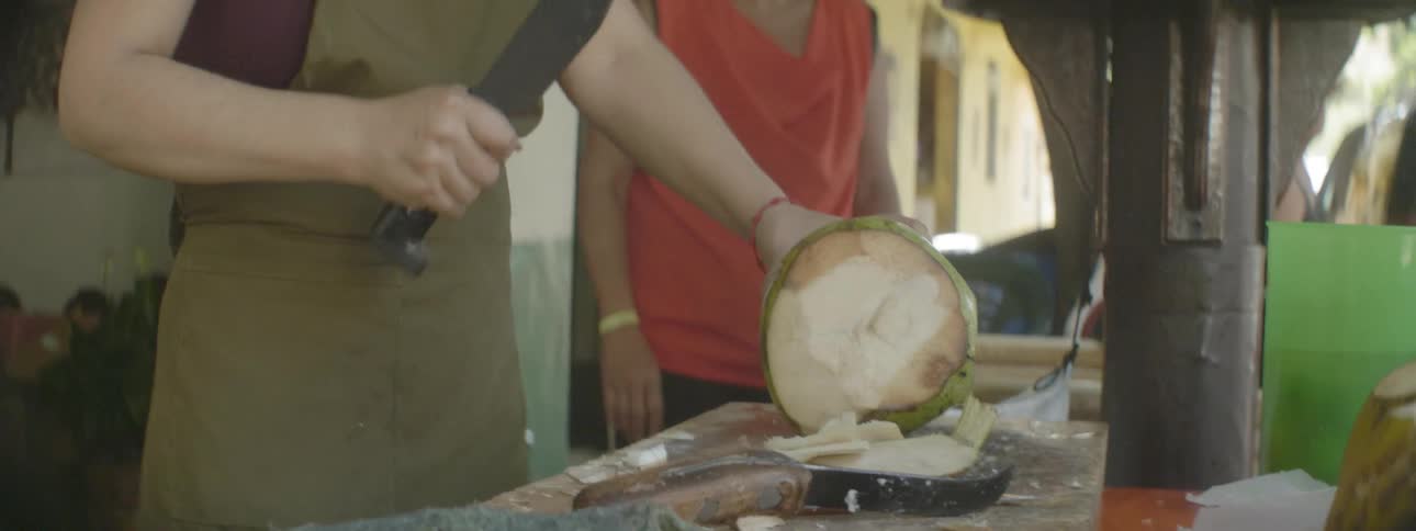 A machete is used to cut a coconut