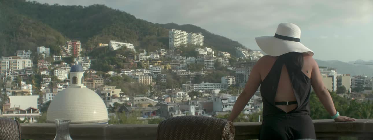 A woman walks to the edge of her balcony
