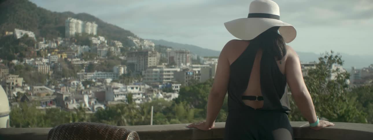 A woman walks over to the balcony to look over the city