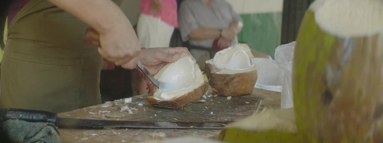 A man is cutting up a coconut