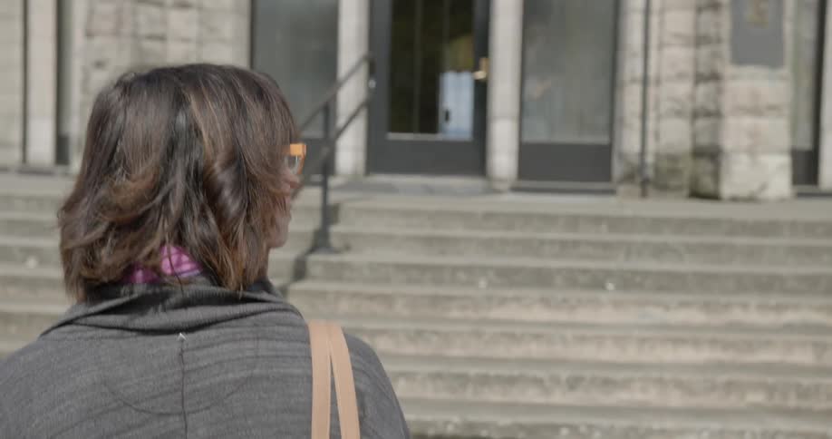 Woman walking up the stairs of a public building