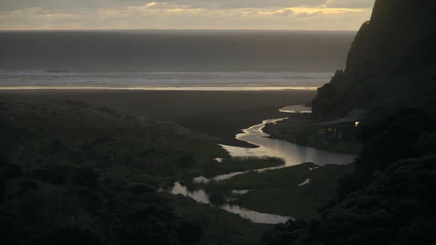 A river at the base of a mountain leads to the ocean