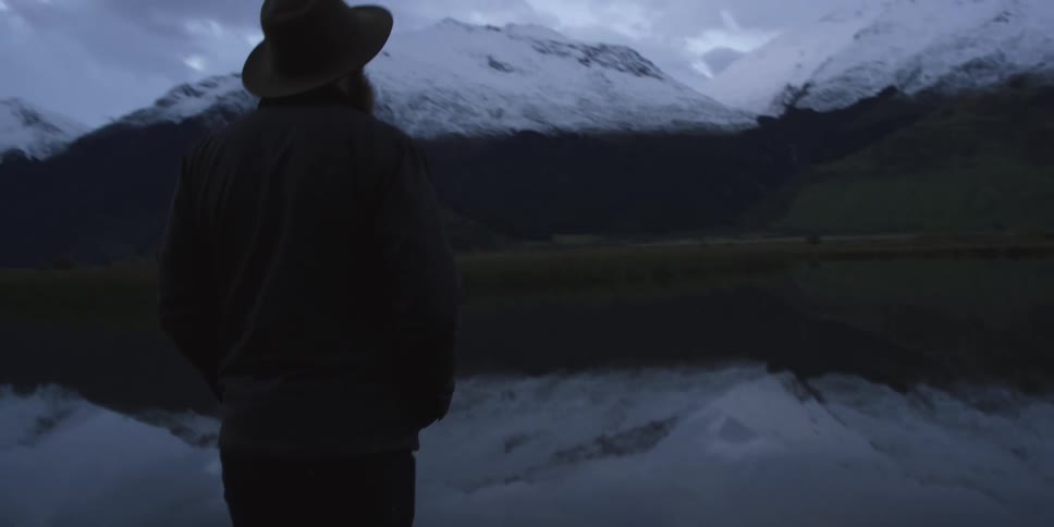 Man stands at the edge of the cliff and looks at the snow covered mountains