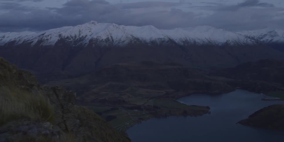 Aerial view of the tops of mountains then a lake at sunset