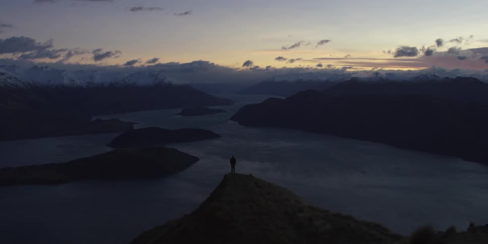A person stands at a peak overlooking a river