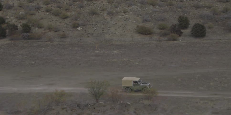 A jeep is moving on a narrow path through a deserted land