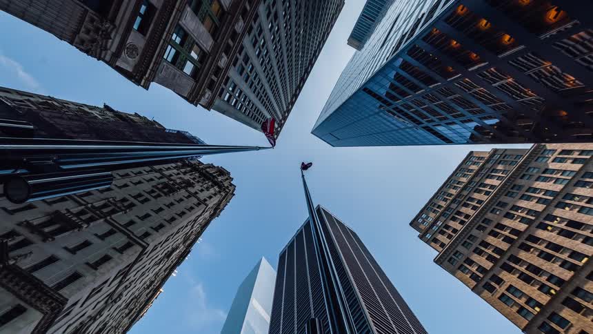 The flags are flying on the top of these tall buildings