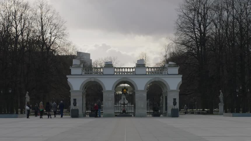 People walk near an historical monument on a cloudy day