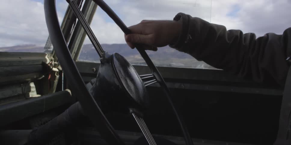 Persons hand steering a vehicle as they travel over a bridge