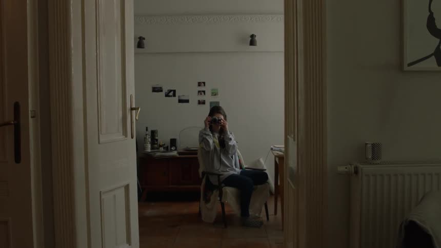 A woman takes a photograph from the other room