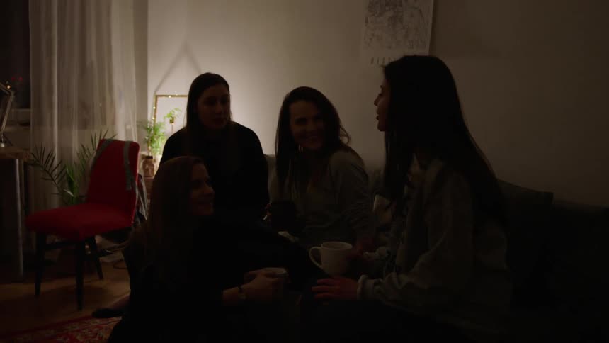 A group of women sit on a couch and talk