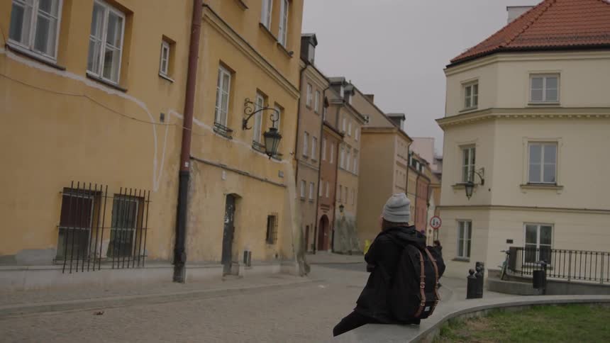 Woman sitting on an edge of a monument as other move around in a city