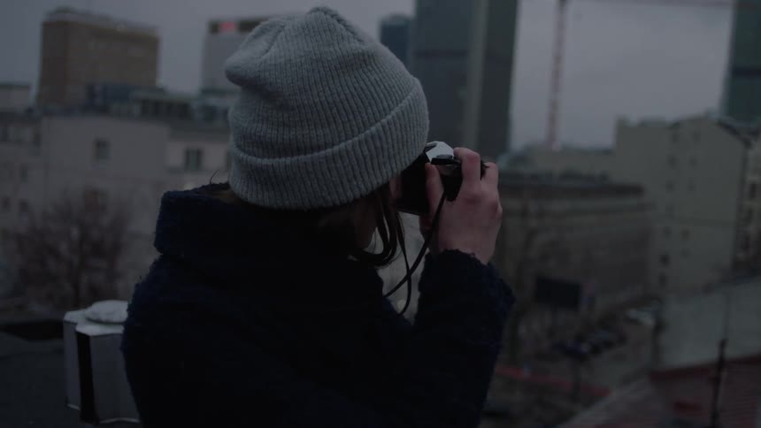 A woman takes pictures from a roof