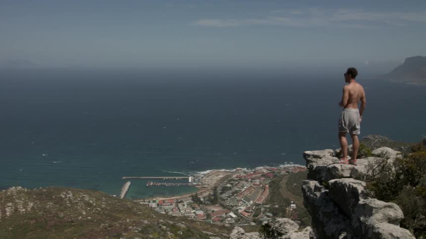 Man standing at the edge of a cliff overlooking an ocean