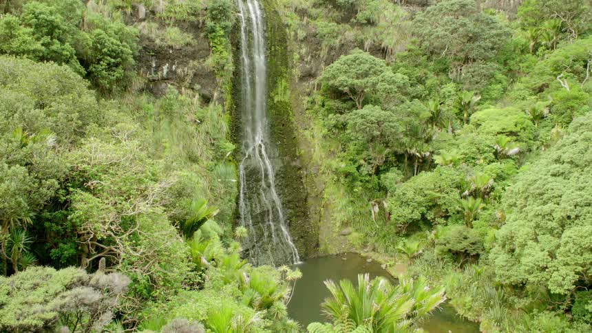 The tall waterfall empties of the pool below