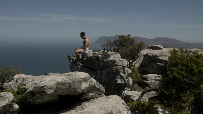 A man is sitting on a mountain on a windy day