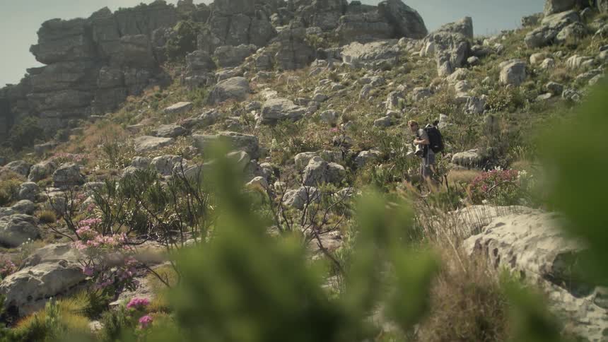 Person wearing a backpack hikes up a rocky hill