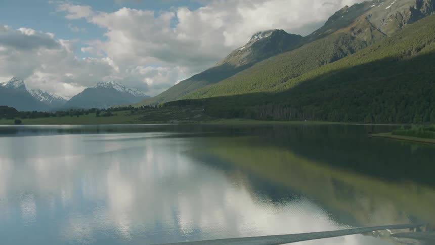 A still lake at the base of forested mountains