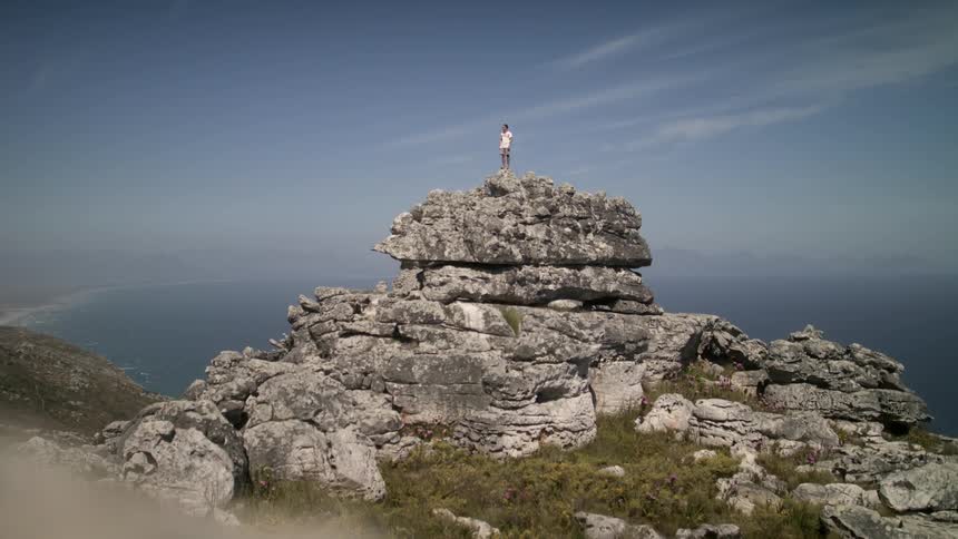 A person stands on top of a mountain on a sunny day