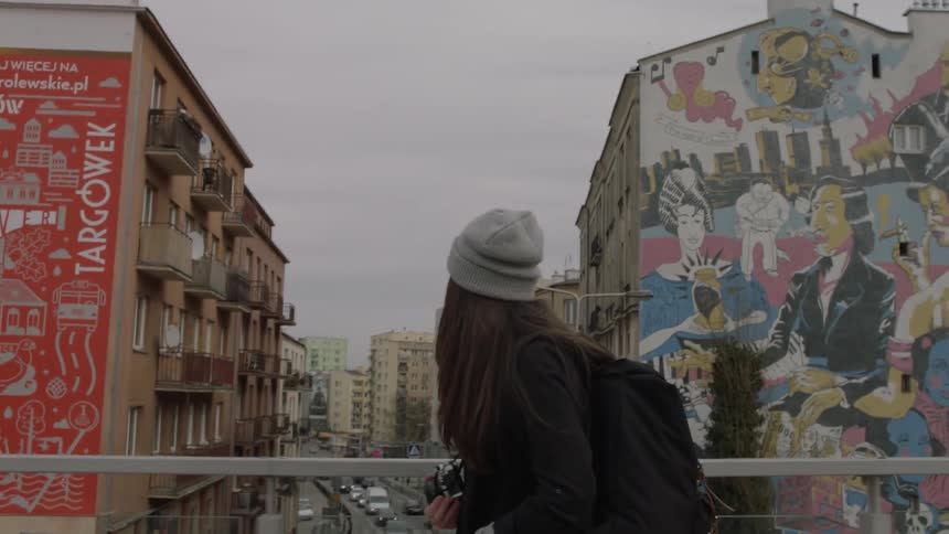 Woman looks at graffiti on buildings as she walks