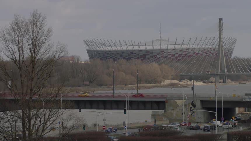 Vehicles pass along a highway by a large stadium