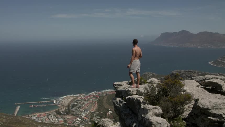 Man stands at the edge of a cliff next to the ocean