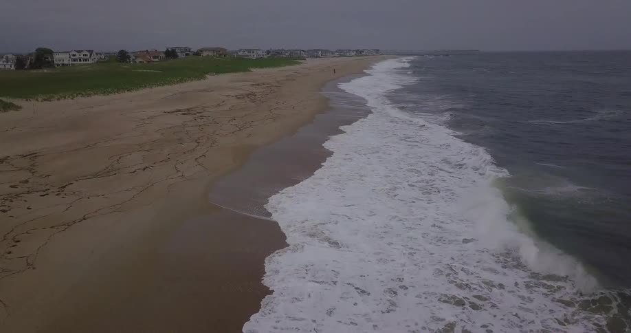 Waves roll onto the shore of a beach on an overcast day