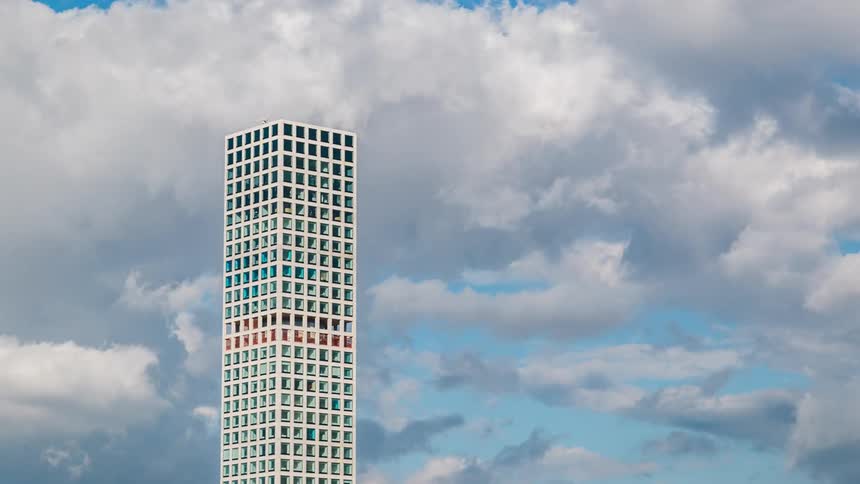 The building is very tall and white reaching the cloudy sky