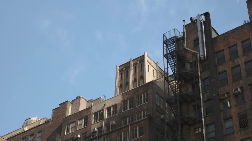 The apartment building fire escape flashes under the sun