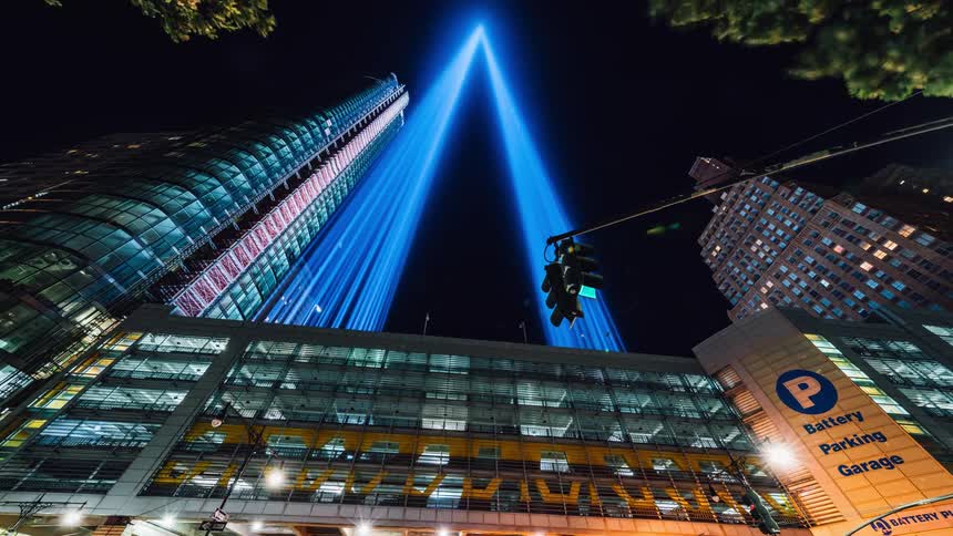 The city is busy at night with lights shining from the top of a building