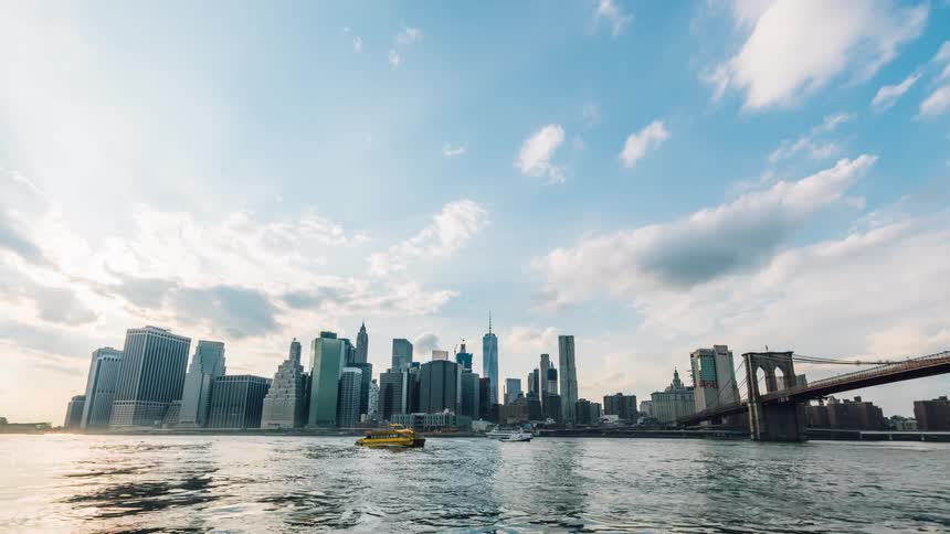 Boats floating down a river next to a large city
