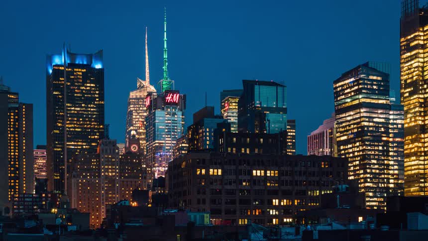 The tall buildings ahead have large antennas at the top of some