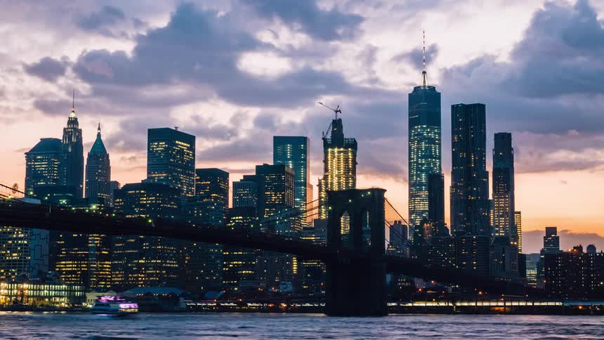 Boats travel under a bridge as clouds move over the city