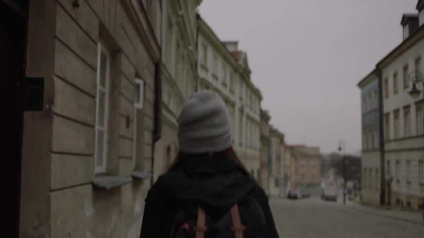A woman walks down a city sidewalk