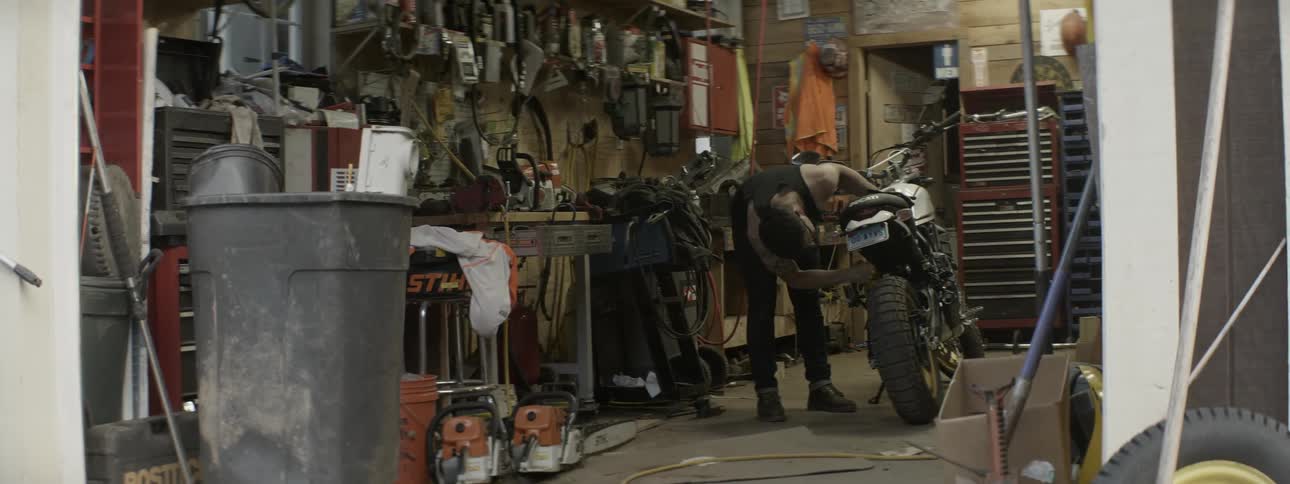 Man turns off his motorcycle and checks the tires in a garage