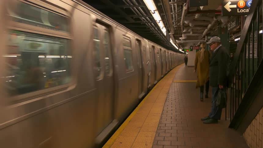 Man stands in a train depot watching the train pass by