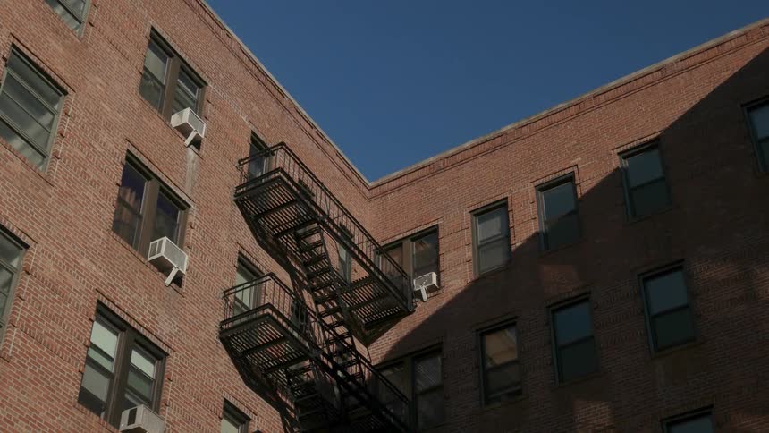 A fire escape is attached to the inside corner of an apartment building