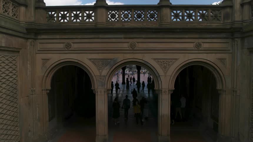Many people walk in an archway of a large building