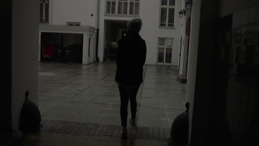 Woman walks through a hallway into a large area near a building