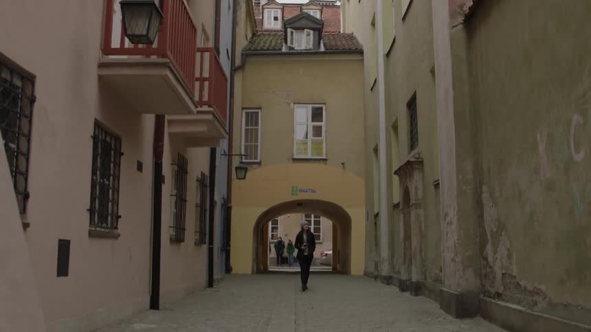 A woman walks down a city alleyway