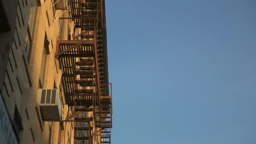 Fire escapes are hanging outside of apartment buildings