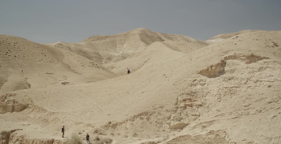People are walking down a hill in the desert